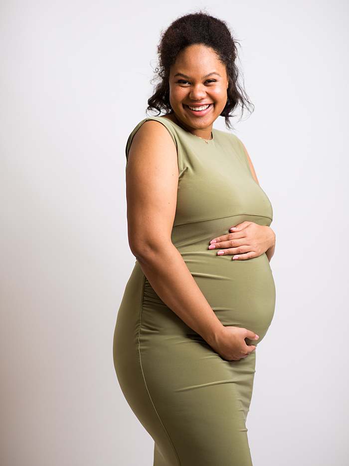 pregnancy-photography-expectant-mother-in-green-dress-smiling-holding-belly